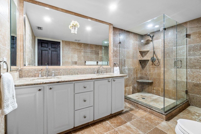 bathroom featuring tile walls, decorative backsplash, vanity, walk in shower, and toilet