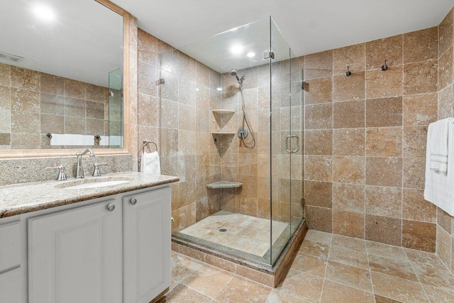 bathroom with vanity, tile walls, backsplash, and a shower with door