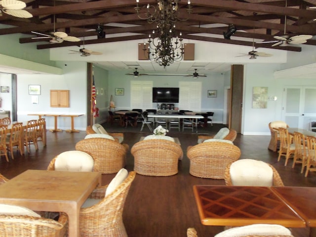 living room with ceiling fan with notable chandelier, dark wood-type flooring, and high vaulted ceiling