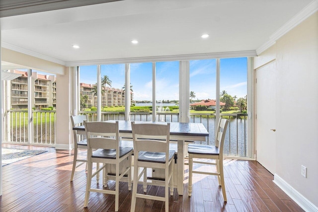 dining room with dark hardwood / wood-style flooring, ornamental molding, and a water view