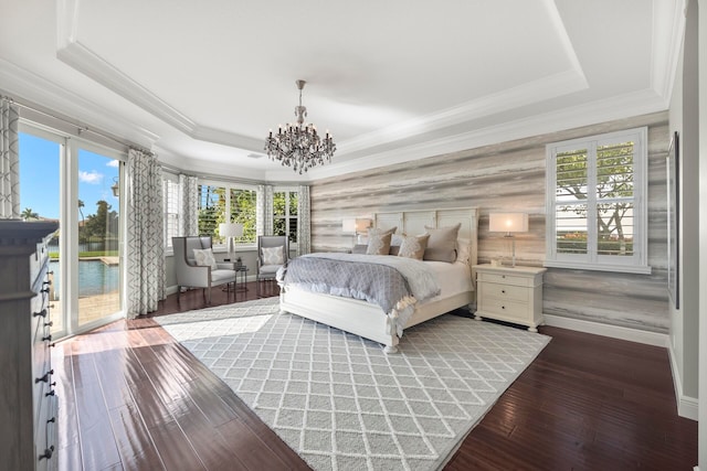 bedroom featuring an inviting chandelier, a raised ceiling, access to exterior, and dark hardwood / wood-style flooring