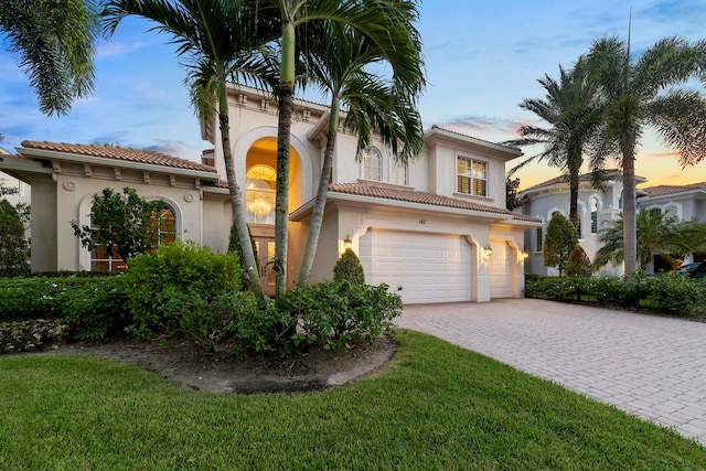 mediterranean / spanish home featuring a garage and a lawn