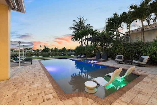 pool at dusk with a patio area