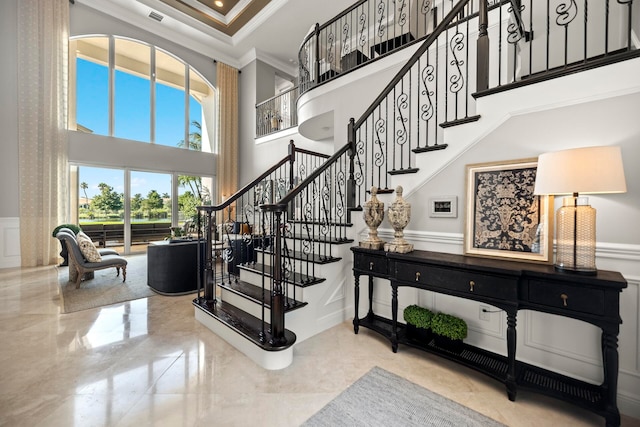 stairs with ornamental molding, a towering ceiling, and a wealth of natural light