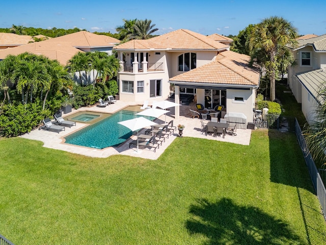 rear view of house featuring a patio, a balcony, a yard, and a swimming pool with hot tub