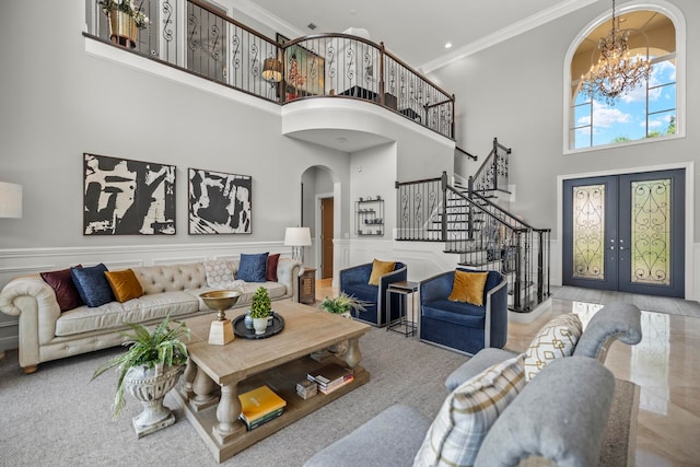 living room with french doors, a notable chandelier, crown molding, and a high ceiling