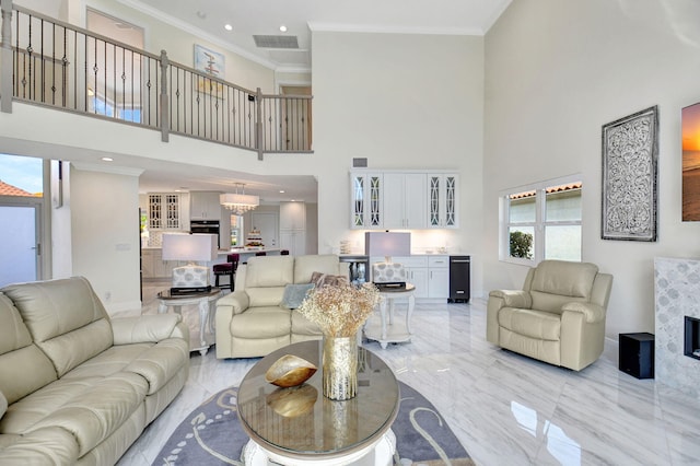 living room with ornamental molding, a notable chandelier, and a high ceiling