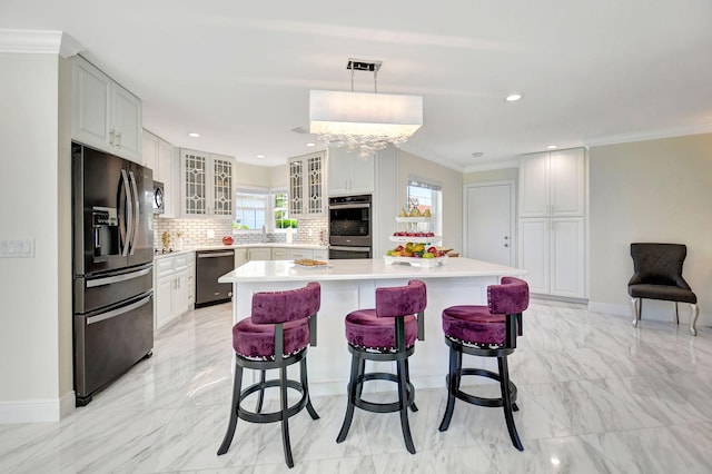 kitchen with appliances with stainless steel finishes, white cabinets, a center island, and decorative light fixtures