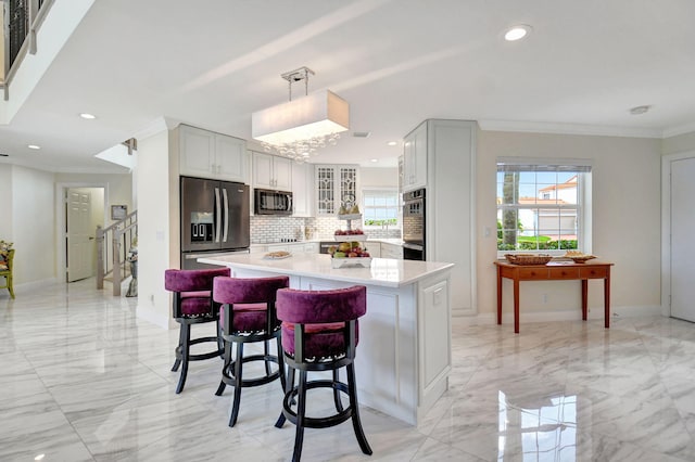 kitchen with hanging light fixtures, decorative backsplash, a breakfast bar, stainless steel appliances, and crown molding