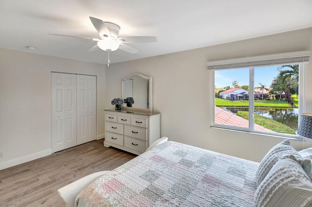 bedroom featuring a water view, a closet, light hardwood / wood-style floors, and ceiling fan