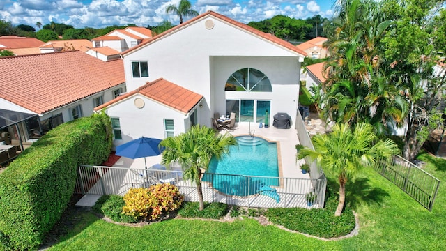 back of house with a fenced in pool, a lawn, and a patio area