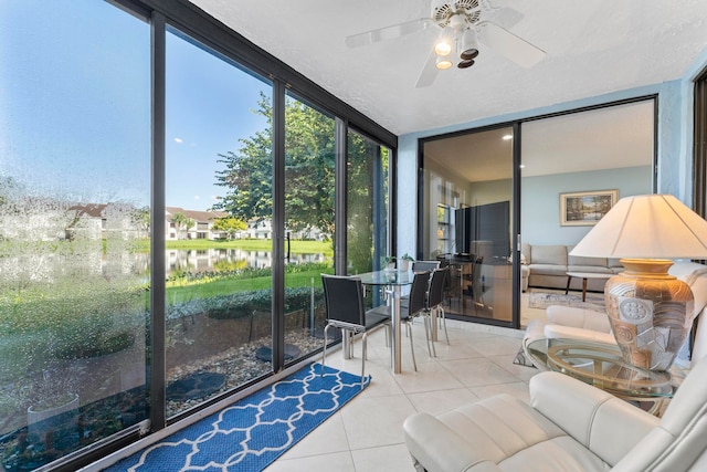 sunroom with ceiling fan and a water view