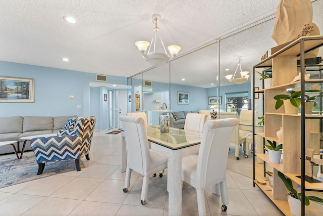 tiled dining room featuring a textured ceiling and a chandelier