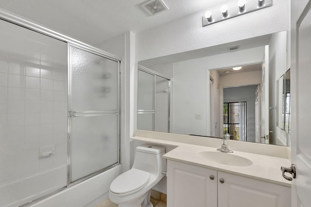 full bathroom featuring a textured ceiling, shower / bath combination with glass door, vanity, and toilet