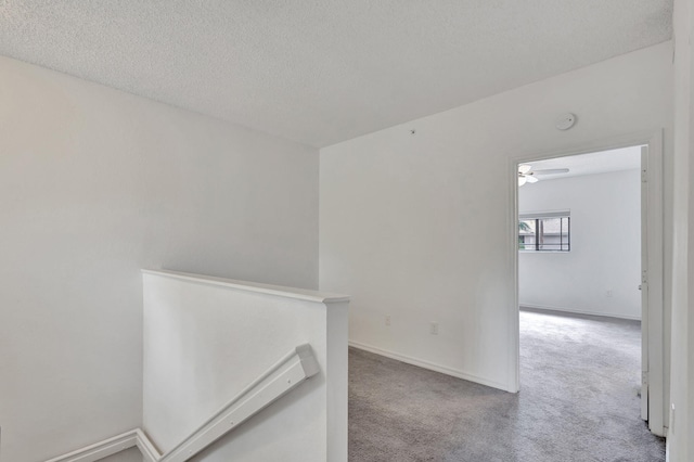 hallway featuring a textured ceiling and light carpet