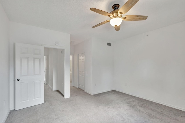 unfurnished bedroom featuring a textured ceiling, light carpet, and ceiling fan