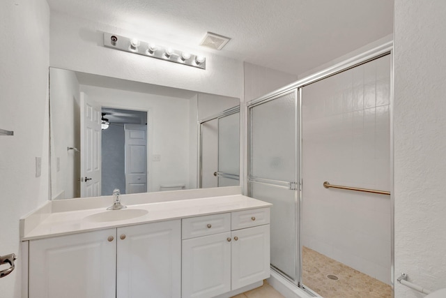 bathroom featuring a shower with shower door, vanity, a textured ceiling, ceiling fan, and toilet