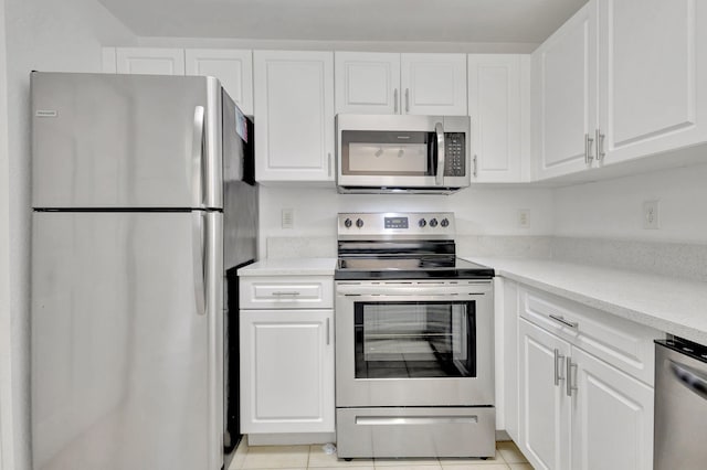 kitchen with white cabinets, light tile patterned flooring, appliances with stainless steel finishes, and light stone countertops