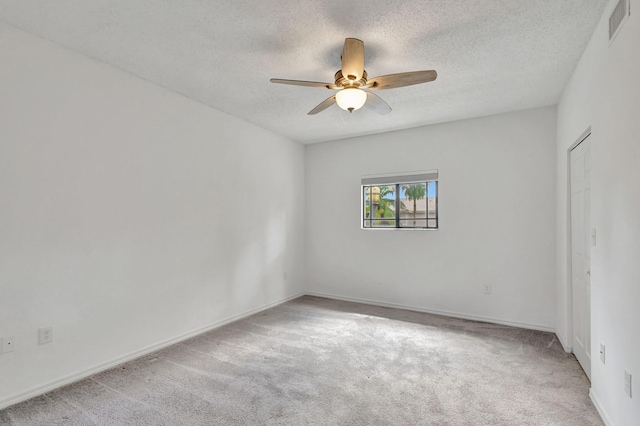 carpeted empty room with ceiling fan and a textured ceiling