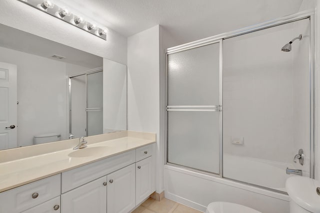 full bathroom with vanity, a textured ceiling, combined bath / shower with glass door, tile patterned floors, and toilet