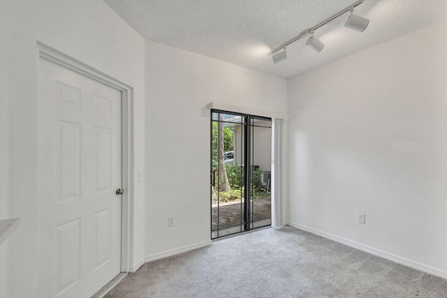 carpeted empty room featuring a textured ceiling and rail lighting