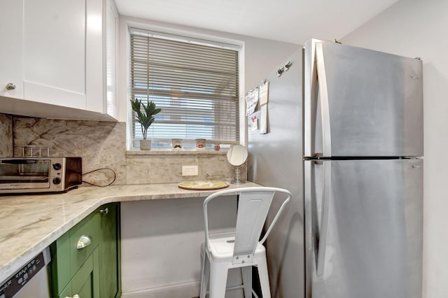 kitchen featuring light stone counters, tasteful backsplash, white cabinets, green cabinetry, and stainless steel appliances