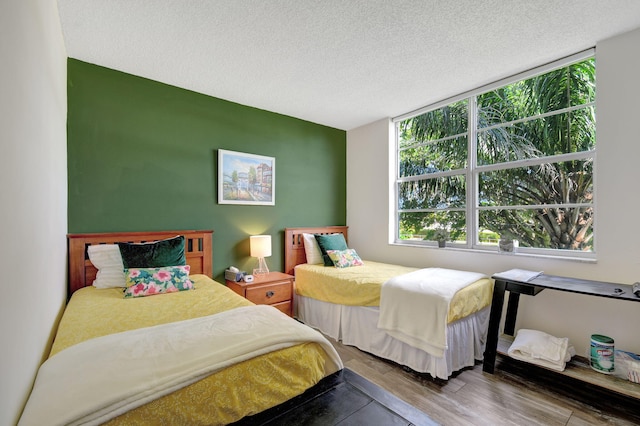 bedroom featuring hardwood / wood-style flooring, a textured ceiling, and multiple windows