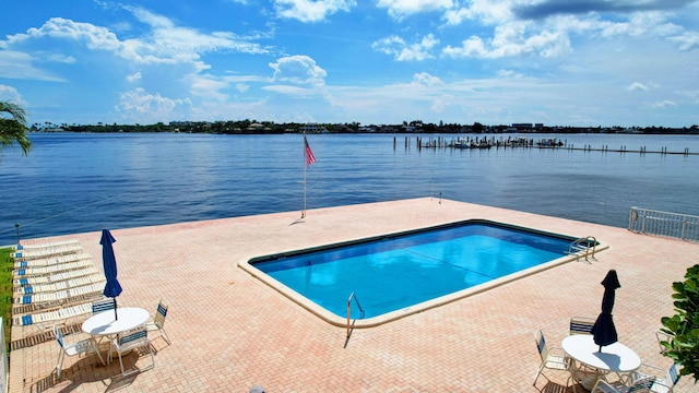 view of swimming pool featuring a patio and a water view