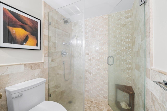 bathroom featuring tile walls, toilet, and a shower with shower door