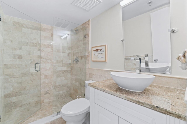 bathroom featuring tile walls, vanity, toilet, and a shower with shower door