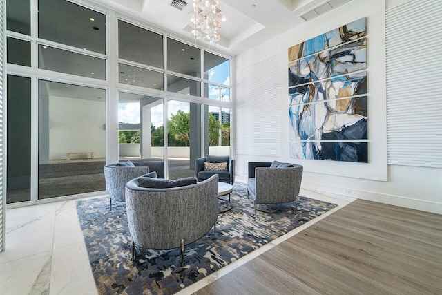 sitting room featuring an inviting chandelier, a high ceiling, hardwood / wood-style floors, and expansive windows