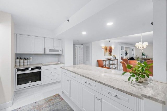 kitchen featuring oven, white cabinetry, tasteful backsplash, and a notable chandelier