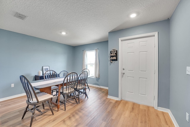 dining room featuring light wood-type flooring and a textured ceiling