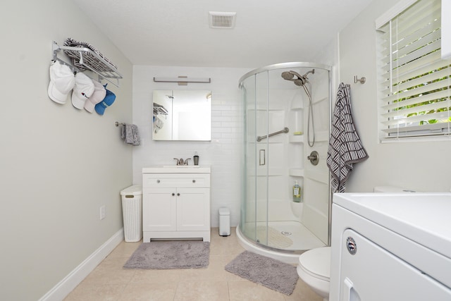 bathroom with tile patterned floors, a shower with door, vanity, and toilet