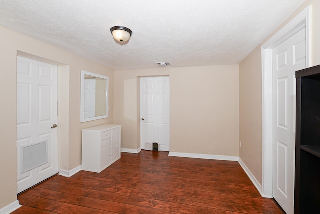 spare room featuring a textured ceiling and dark wood-type flooring