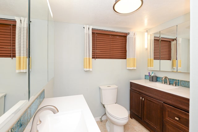 bathroom with vanity, toilet, a textured ceiling, and tile patterned floors