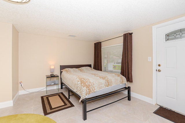 bedroom with a textured ceiling and light tile patterned floors