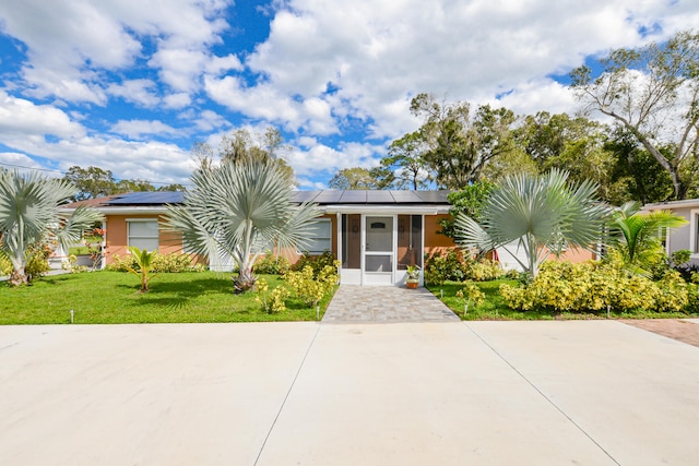 view of front of home featuring a front yard and solar panels