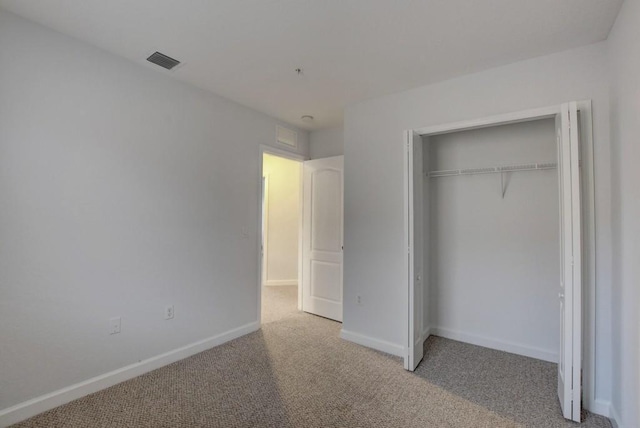 unfurnished bedroom with a closet and light colored carpet