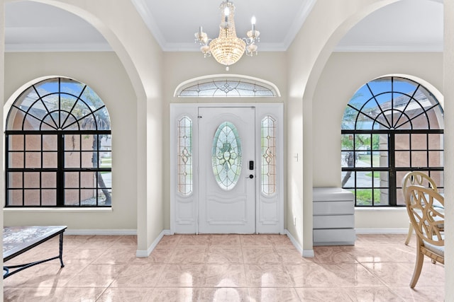 foyer entrance with ornamental molding, a chandelier, and a wealth of natural light