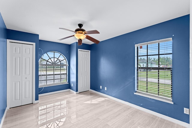 unfurnished bedroom with multiple closets, multiple windows, and ceiling fan