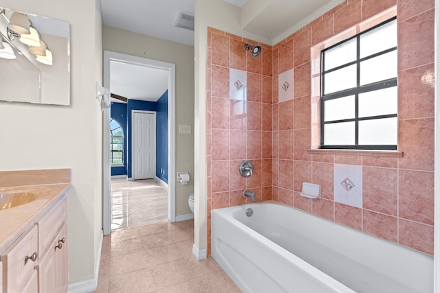 full bathroom featuring tiled shower / bath, vanity, toilet, and tile patterned flooring