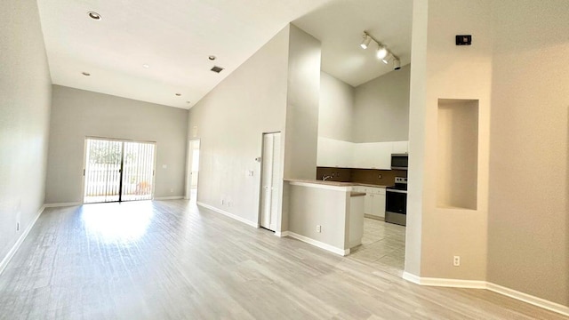 unfurnished living room with rail lighting, light hardwood / wood-style floors, and high vaulted ceiling