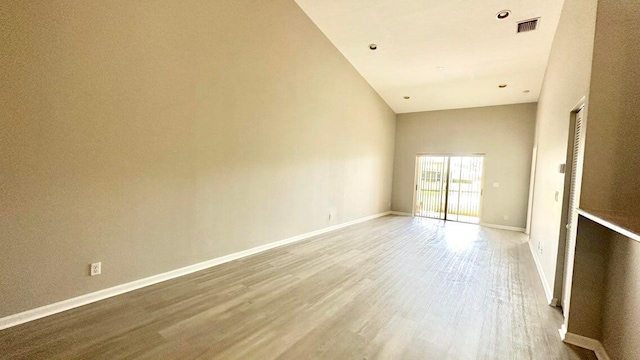 spare room featuring hardwood / wood-style floors and high vaulted ceiling