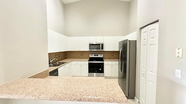 kitchen with sink, kitchen peninsula, white cabinetry, stainless steel appliances, and high vaulted ceiling