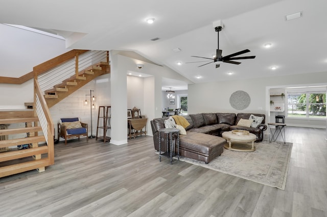 living room with lofted ceiling, ceiling fan with notable chandelier, and light wood-type flooring