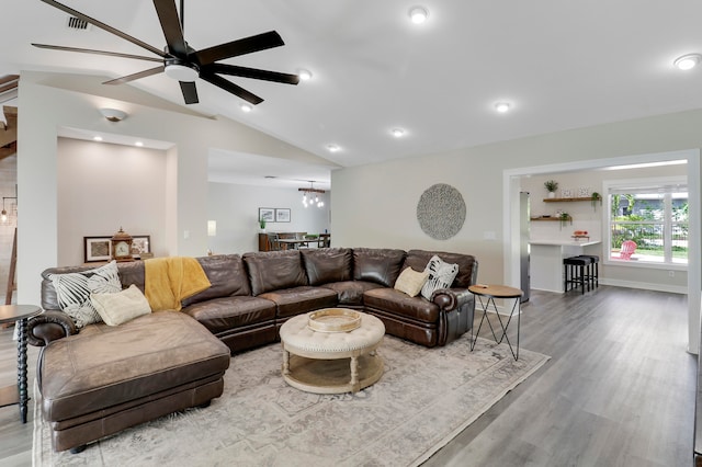 living room featuring wood-type flooring, ceiling fan with notable chandelier, and vaulted ceiling