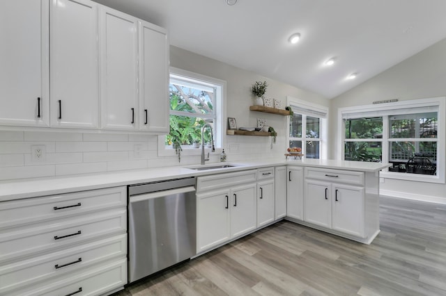 kitchen featuring tasteful backsplash, stainless steel dishwasher, vaulted ceiling, sink, and white cabinets