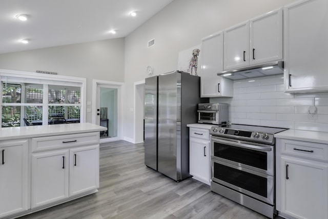 kitchen featuring stainless steel appliances, white cabinetry, and lofted ceiling