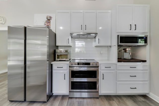 kitchen featuring tasteful backsplash, white cabinets, stainless steel appliances, and light hardwood / wood-style floors